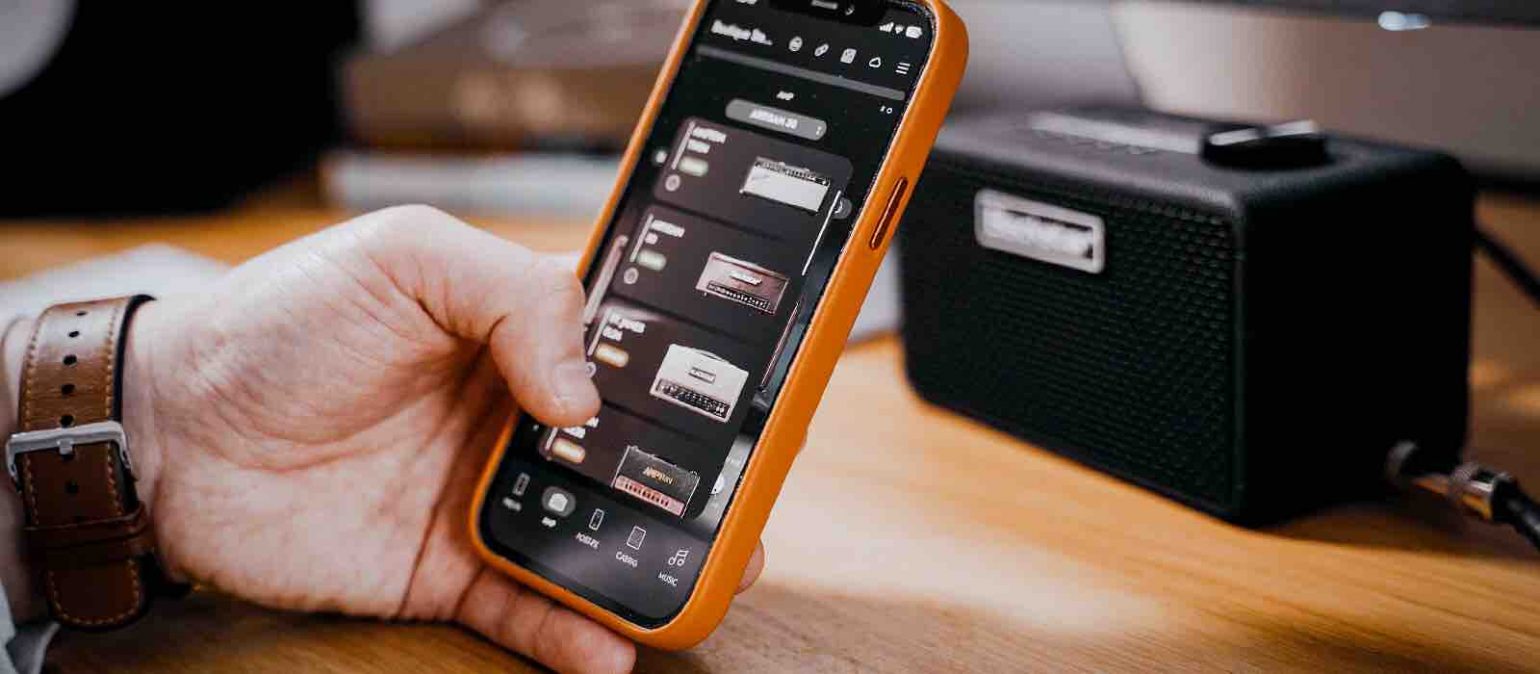A smartphone displaying the Blackstar tone-editing app next to the Beam Mini speaker, showing the photo-realistic virtual guitar rig and pedals.