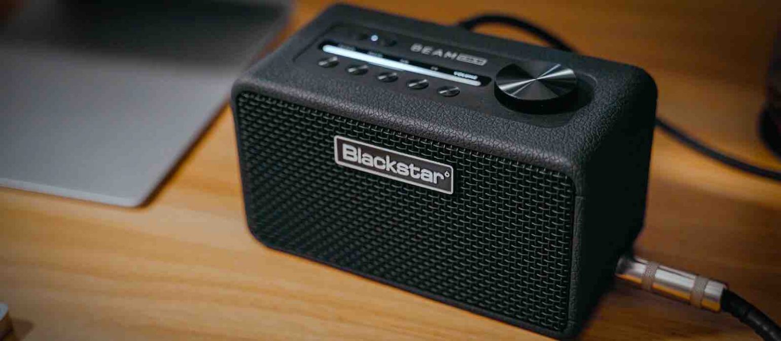 Front view of the Blackstar Beam Mini desktop guitar amplifier showing the dynamic Light Beam LED display, SpeedDial control, and sleek black mesh grille.