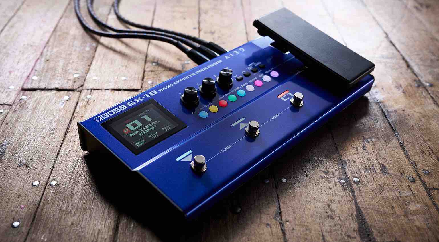 Top-down view of the GX-1B bass multi-effects processors showing the color display, three footswitches, and built-in expression pedal.