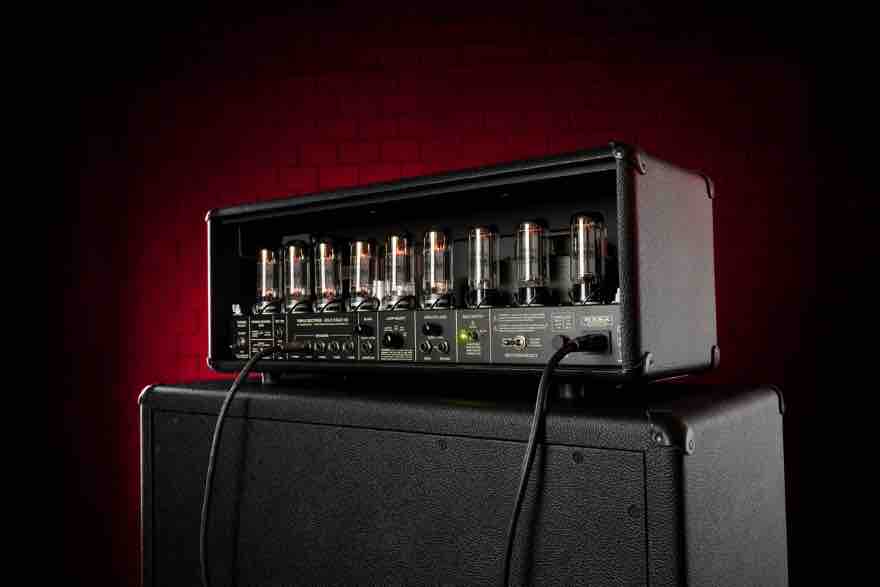Close-up of the internal power section of a MESA/Boogie Triple Rectifier featuring six 6L6 vacuum tubes and five 12AX7 preamp tubes glowing inside the chassis.