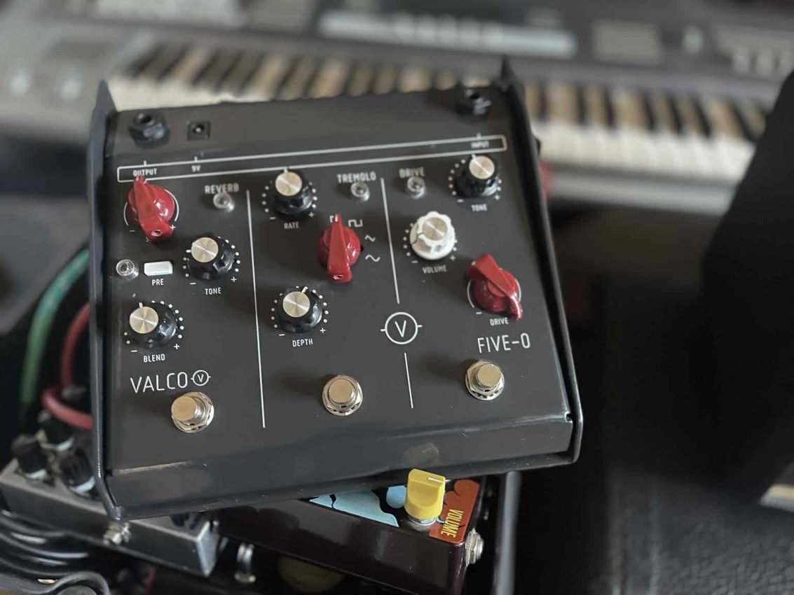 A top-down view of the Valco Five-O multi-effects pedal featuring a large wedge-shaped grey metal enclosure, top-mounted jacks, three independent footswitches for Drive, Tremolo, and Reverb, and a unique "PRE" routing button.